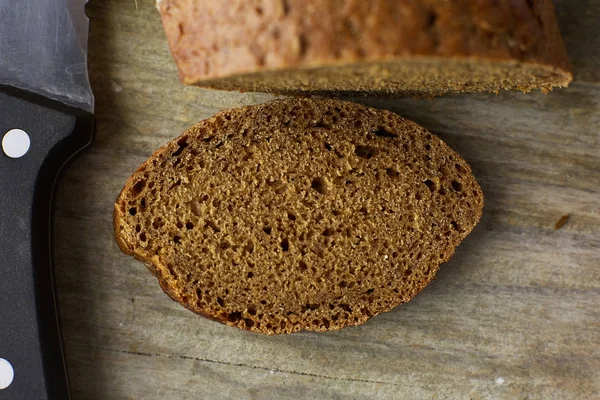 Gesneden brood van brood en mes op houten tafel. Bijgesneden foto. — Stockfoto