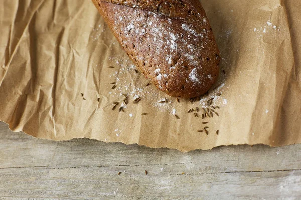 En brödlimpa förpackad i papper på träbord. — Stockfoto