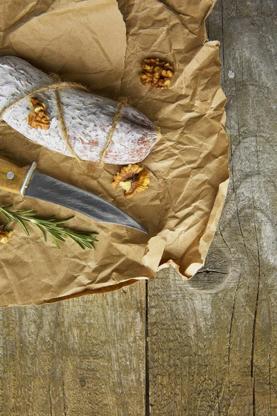 全体イタリアのサラミ wih ローズマリー、紙の上のナイフです。素朴なスタイル。トップ ビュー. — ストック写真