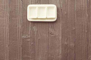 Ahşap masa zemininde kare şeklinde boş seramik tabaklar, üst görünüm.