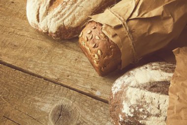 Tahta masanın üzerinde kağıda sarılı bir somun ekmek..