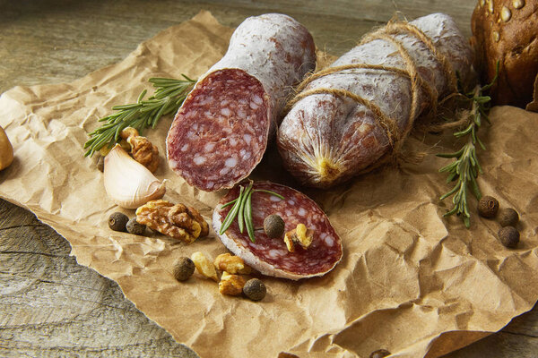 Italian salami wih sea salt, rosemary, garlic and nuts on paper. Rustic style. Close up.