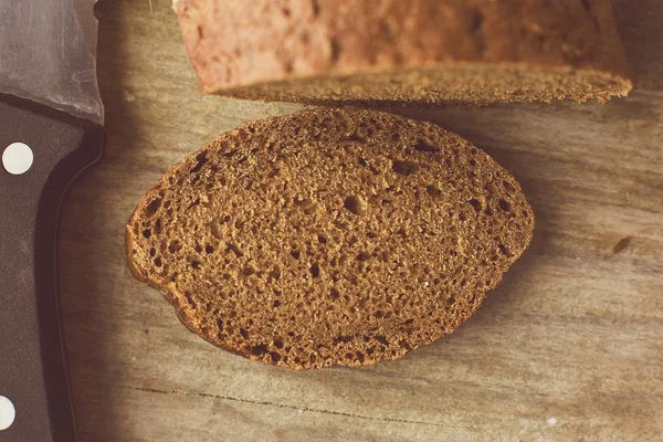 Gesneden brood van brood en mes op houten tafel. Bijgesneden foto. — Stockfoto