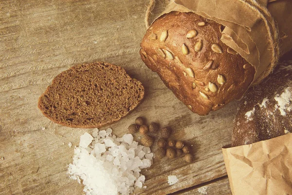 Két kenyér kenyeret csomagolva papírt a fából készült asztal . — Stock Fotó