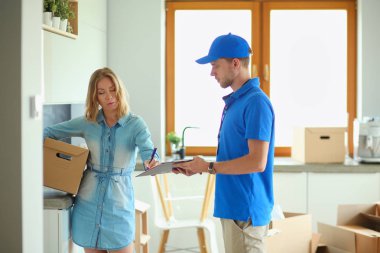 Mavi üniformalı gülümseyen kurye servis konseptine paket kutusu teslim eden teslimatçı. Mavi üniformalı gülümseyen teslimatçı.