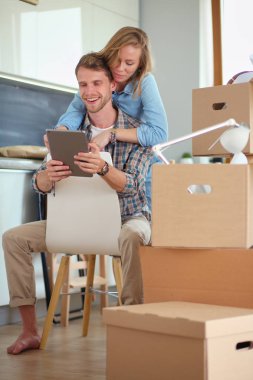 Genç bir çift yeni ev içinde hareket. Oturma ve açma sonra rahatlatıcı. Bir şey üstünde laptop arıyorum. Genç Çift