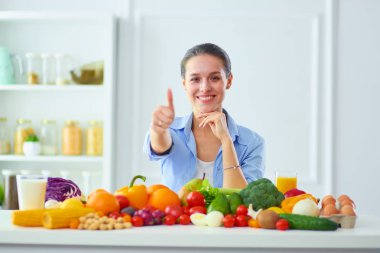 Ahşap iç kısımda meyve ve sebze dolu masada oturan genç ve tatlı bir kadın..