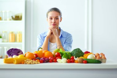 Ahşap iç kısımda meyve ve sebze dolu masada oturan genç ve tatlı bir kadın..