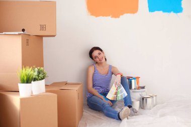 Kadın seçerek boya rengi renk örneği yeni ev ahşap yere oturmak için. Kadın evde