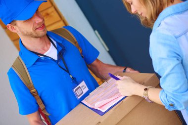 Mavi üniformalı gülümseyen kurye servis konseptine paket kutusu teslim eden teslimatçı. Mavi üniformalı gülümseyen teslimatçı.