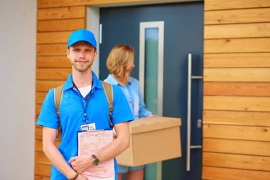 Mavi üniformalı gülümseyen kurye servis konseptine paket kutusu teslim eden teslimatçı. Mavi üniformalı gülümseyen teslimatçı.