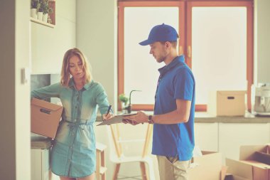 Mavi üniformalı gülümseyen kurye servis konseptine paket kutusu teslim eden teslimatçı. Mavi üniformalı gülümseyen teslimatçı.