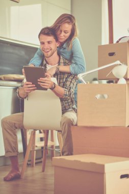 Genç bir çift yeni ev içinde hareket. Oturma ve açma sonra rahatlatıcı. Bir şey üstünde laptop arıyorum. Genç Çift