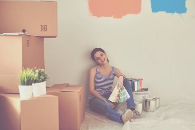 Kadın seçerek boya rengi renk örneği yeni ev ahşap yere oturmak için. Kadın evde