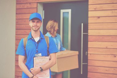 Mavi üniformalı gülümseyen kurye servis konseptine paket kutusu teslim eden teslimatçı. Mavi üniformalı gülümseyen teslimatçı.