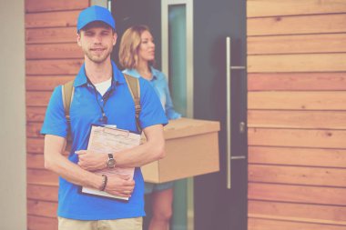 Mavi üniformalı gülümseyen kurye servis konseptine paket kutusu teslim eden teslimatçı. Mavi üniformalı gülümseyen teslimatçı.