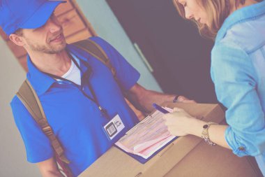Mavi üniformalı gülümseyen kurye servis konseptine paket kutusu teslim eden teslimatçı. Mavi üniformalı gülümseyen teslimatçı.