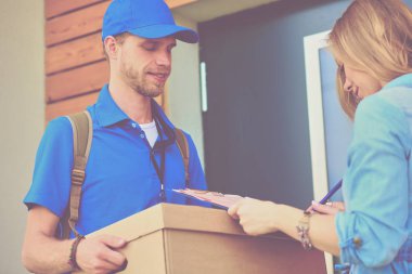 Mavi üniformalı gülümseyen kurye servis konseptine paket kutusu teslim eden teslimatçı. Mavi üniformalı gülümseyen teslimatçı.