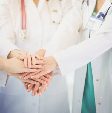 Doktorlar ve hemşireler tıbbi bir ekipte el ele tutuşuyorlar.