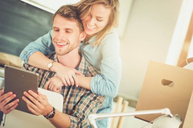 Genç bir çift yeni ev içinde hareket. Oturma ve açma sonra rahatlatıcı. Bir şey üstünde laptop arıyorum. Genç Çift