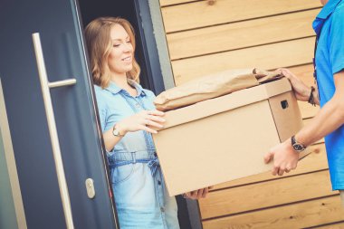 Mavi üniformalı gülümseyen kurye servis konseptine paket kutusu teslim eden teslimatçı. Mavi üniformalı gülümseyen teslimatçı.
