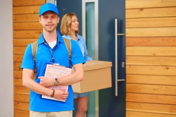 Mavi üniformalı gülümseyen kurye servis konseptine paket kutusu teslim eden teslimatçı. Mavi üniformalı gülümseyen teslimatçı. — Stok fotoğraf