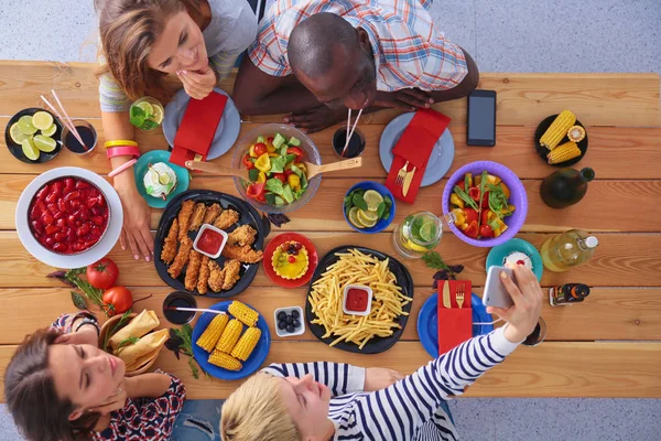 Vue du dessus du groupe de personnes qui dînent ensemble tout en étant assis à une table en bois. De la nourriture sur la table. Les gens mangent fast food. — Photo