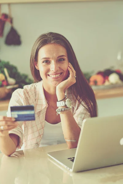 Lachende vrouw online winkelen met behulp van tablet en creditcard in de keuken. Glimlachende vrouw — Stockfoto