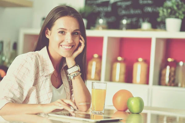 Een jonge vrouw in de keuken, die haar ipad gebruikt. Jonge vrouw — Stockfoto