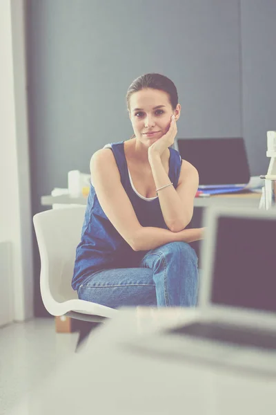 Ung kvinna sitter vid skrivbordet med instrument, plan och laptop. — Stockfoto