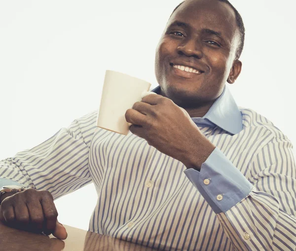 Afrikansk man med kopp te, sitter på skrivbordet — Stockfoto