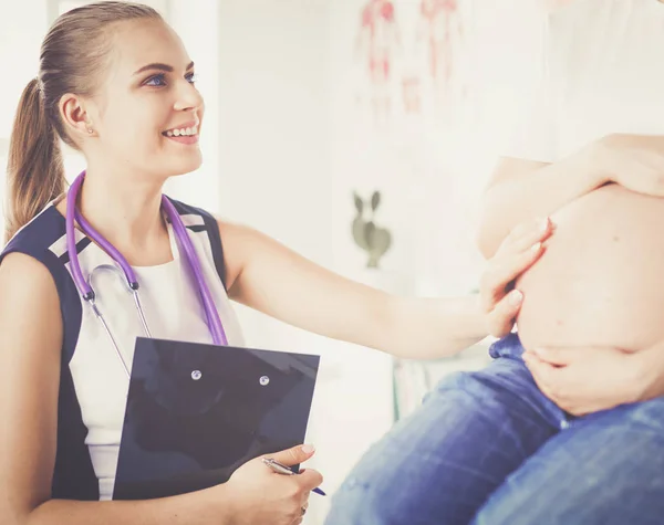 Doctora joven examinando a una mujer embarazada en la clínica. — Foto de Stock