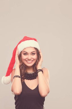 gülümseyen bir Noel Baba şapkası giyen güzel bir kadın portresi.