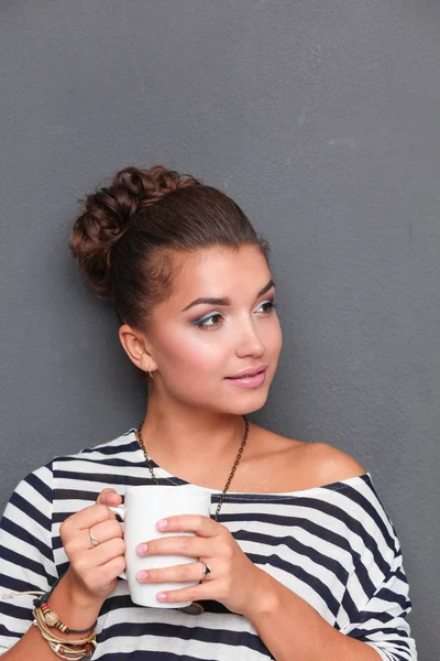 Young woman standing with cup, isolated on gray background. Young woman — Stock Photo, Image