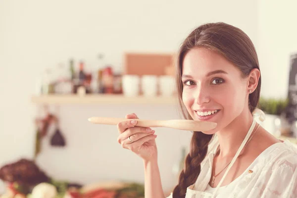Cooking woman in kitchen with wooden spoon. Cooking woman