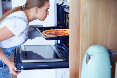 Mutlu genç bayan evde pizza pişiriyor.
