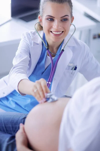 Ung kvinnlig läkare undersöker gravid kvinna på kliniken. — Stockfoto