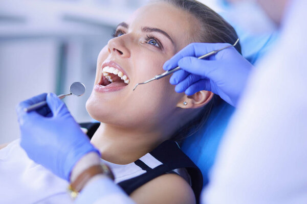 Young Female patient with open mouth examining dental inspection at dentist office.