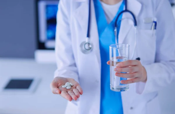 Close-up shot of doctors hands holding pills and glass of water. — Stock Photo, Image