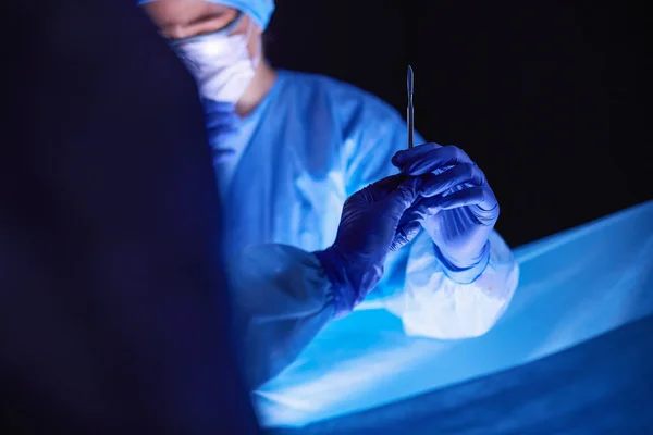 stock image Doctors team in surgery in a dark background.