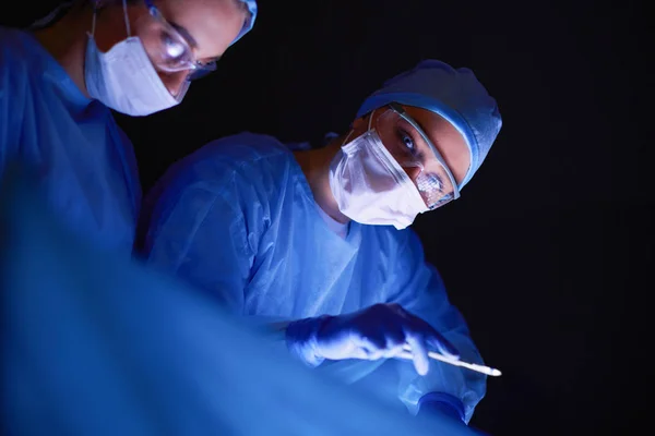 Artsen team in de chirurgie in een donkere achtergrond. — Stockfoto