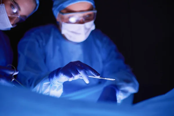 Cropped picture of scalpel taken doctors performing surgery. — Stock Photo, Image