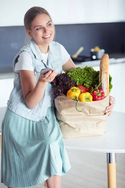 Young woman holding grocery shopping bag with vegetables .Standing in the kitchen — Stock Photo, Image