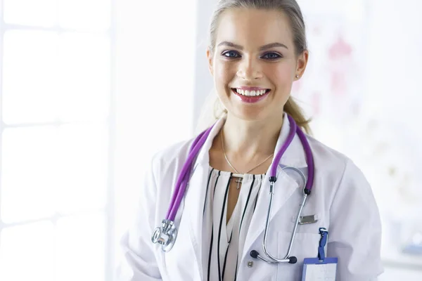 Médica sorridente com estetoscópio médico de pé uniforme — Fotografia de Stock