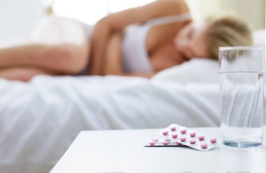 Genç, güzel bir kadın. Yatağında haplarla yatıyor.