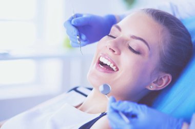 Dişçi muayenehanesinde diş muayenesi yapan ağzı açık genç bir kadın hasta..