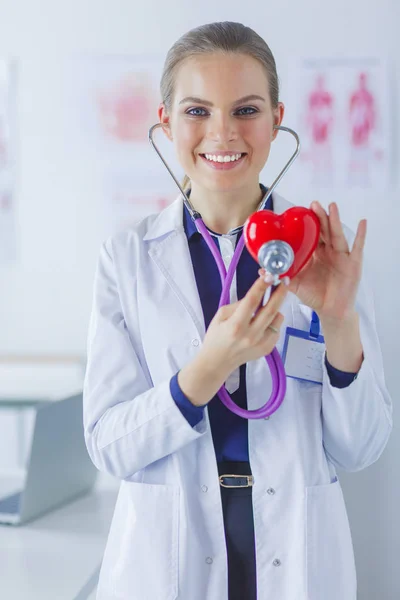 Un médecin avec stéthoscope examinant le cœur rouge, isolé sur fond blanc — Photo