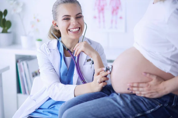 Улыбающаяся женщина врач показывает фотографии на планшете беременной девушке в больнице. — стоковое фото