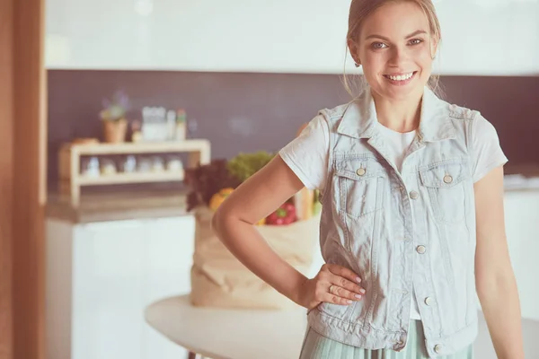 Jonge vrouw met boodschappentas met groenten.Staande in de keuken — Stockfoto