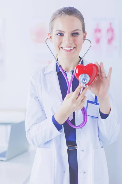 Ein Arzt mit Stethoskop untersucht rotes Herz, isoliert auf weißem Hintergrund — Stockfoto